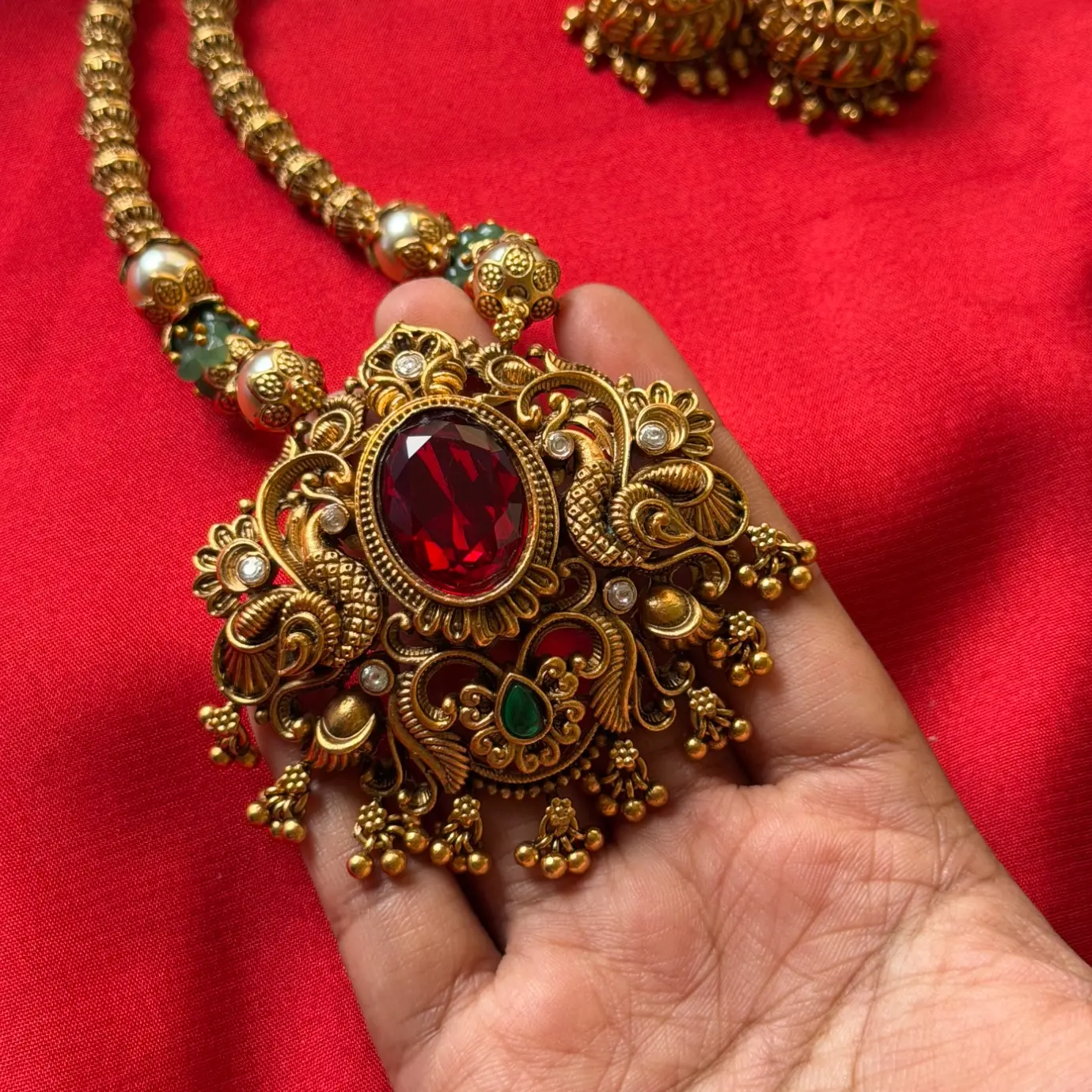 Gold Replica Antique Ruby Oval Solitaire Filigree Pendant Necklace Set – Beaded Mala Chain with Emerald & Pearl Accents, and Matching Temple Jhumkas